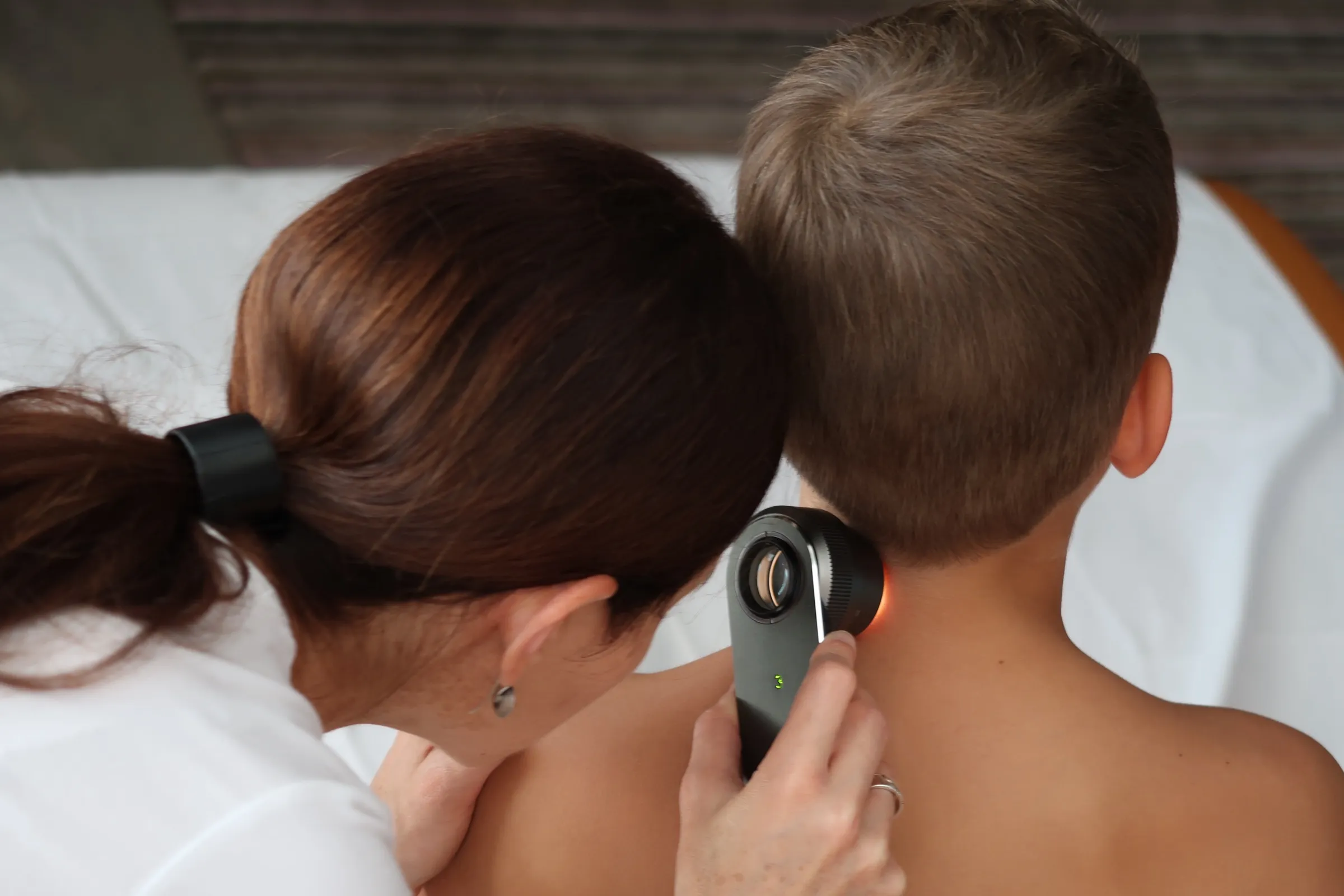 Dr. Krisztina Siklós examining a mole on a child's back with a dermatoscope
